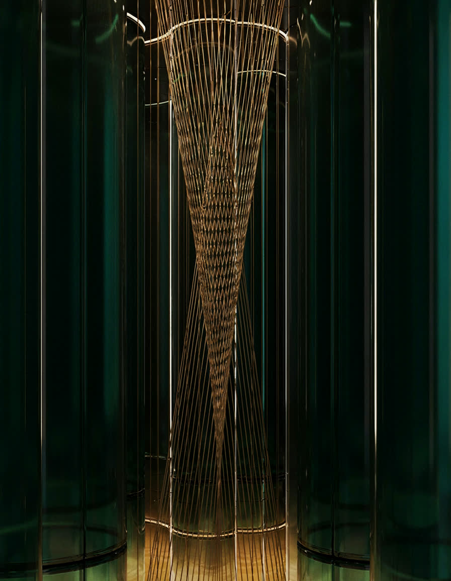Golden wire threads stretched inside a column of emerald glass