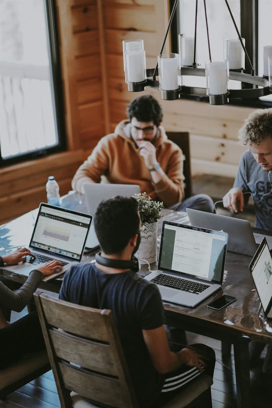 Four people working on laptops around a shared wooden table